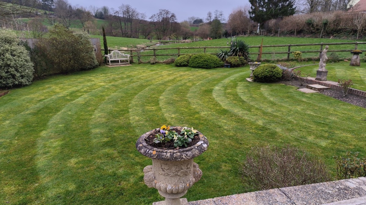 A striped, freshly mown lawn with an ornamental planted urn and rolling Dorset countryside beyond